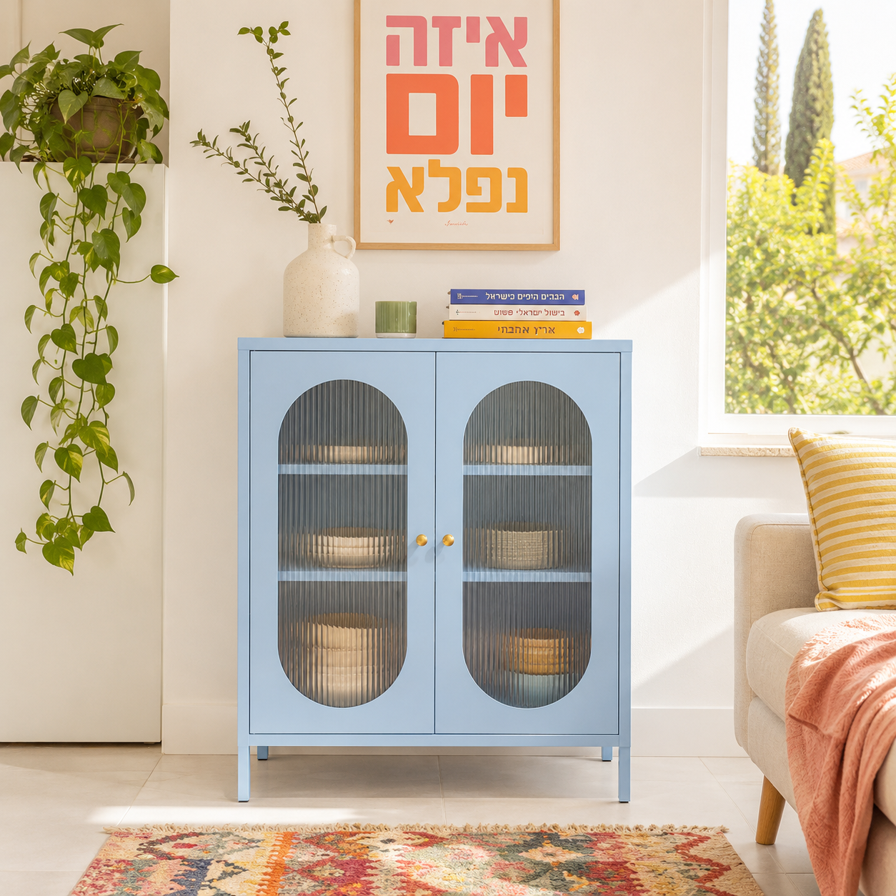 מזנון בצבע תכלת עם שתי דלתות זכוכית מפוספסת קשתיות וידיות זהב, בסלון ליד ספה וכריות