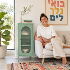 מזנון ירוק מנטה עם דלת זכוכית מפוספסת בסלון ביתי, לצד ספה ושטיח צבעוני