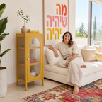 מזנון צהוב חרדל עם דלת זכוכית מפוספסת בסלון ביתי, לצד ספה ושטיח צבעוני